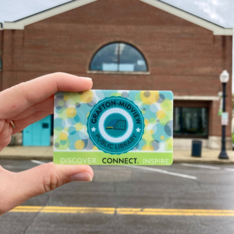hand holding card outside in front of building