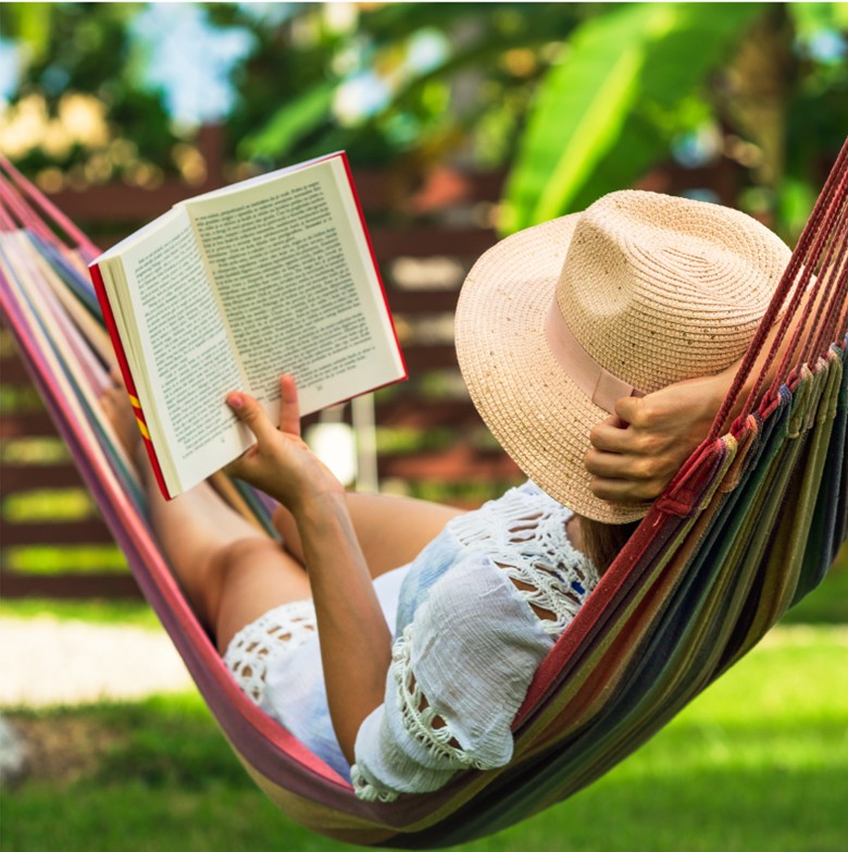 Adult reading a book outside on a hammock